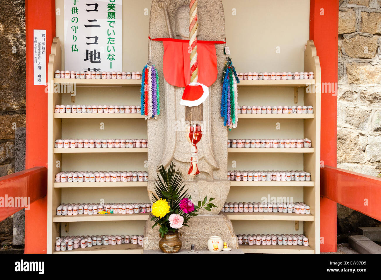 Grand Jizo japonais, alias Ojizo-sama, statue Jizo bosatsu, avec des centaines de minuscules derrière sur des supports à la temple Senkoji, Onomichi, le Japon. Banque D'Images