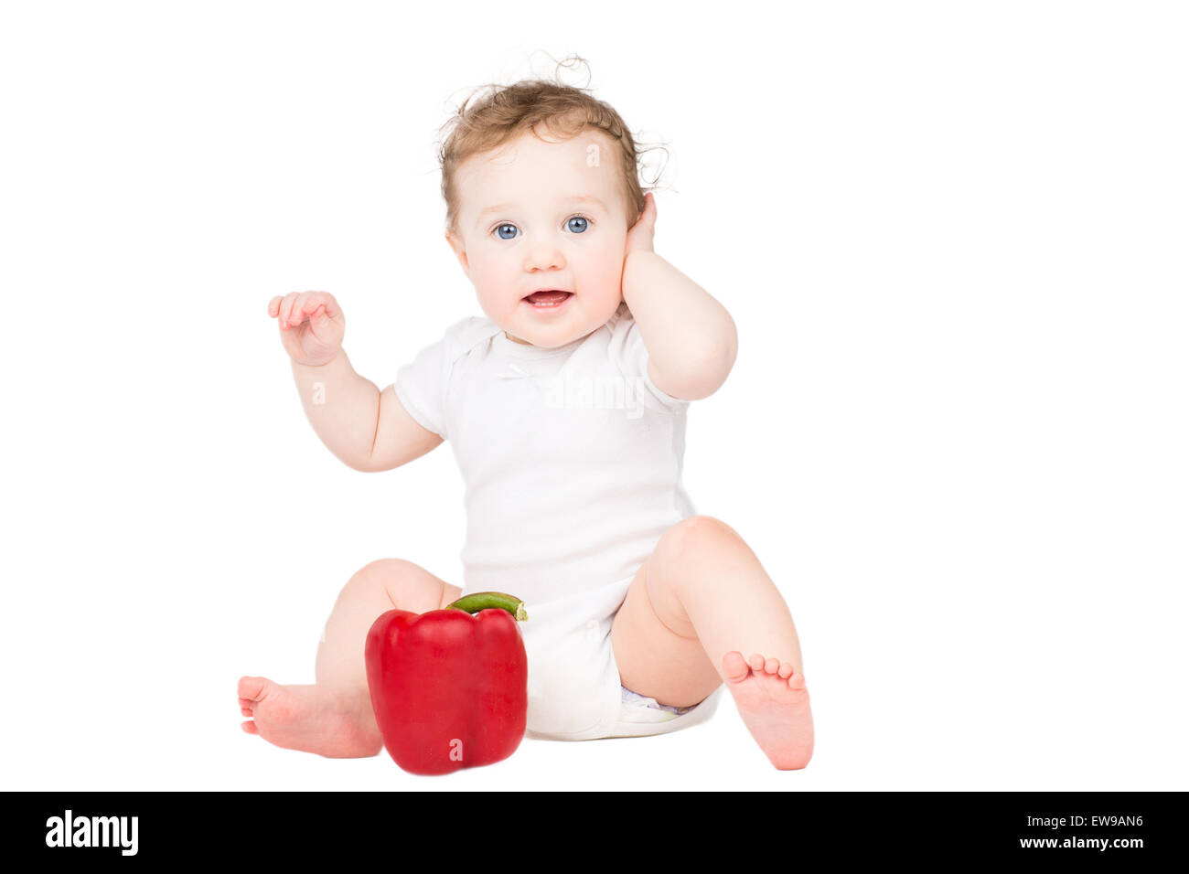 Mignon bébé avec les cheveux bouclés jouant avec un big red paprika, isolated on white Banque D'Images