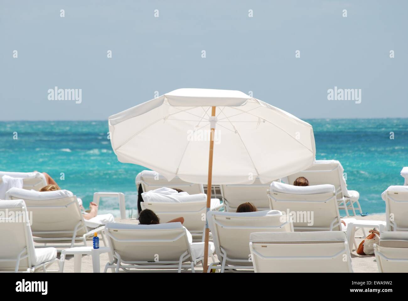 Les gens se détendent et bronzer sur des chaises longues blanches avec parasol blanc, South Beach, Miami, Floride, États-Unis. Banque D'Images Les gens se détendent et bronzer sur des chaises longues blanches avec parasol blanc, South Beach, Miami, Floride, États-Unis. Banque D'Images