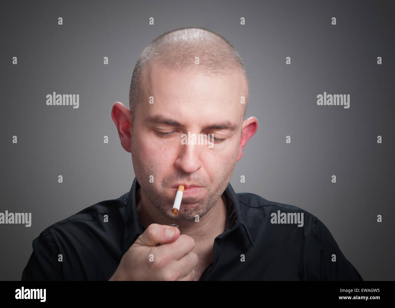 Homme allumer une cigarette et isolé sur fond sombre. Banque D'Images