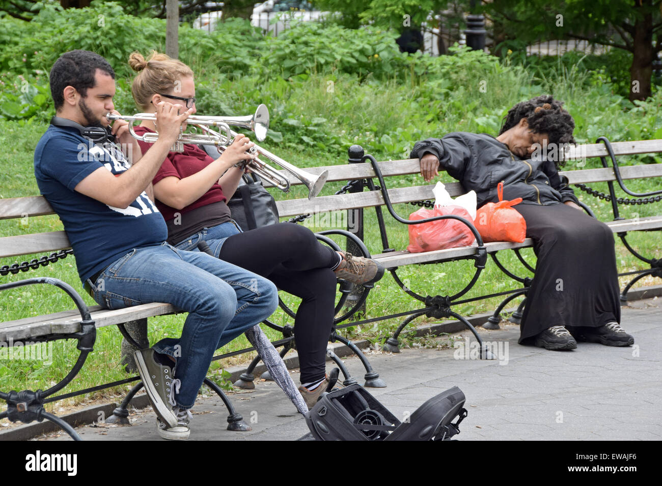 Un jeune homme et femme jouer de la trompette à Washington Square Park à New York alors qu'une femme endormie est indifférent au bruit. Banque D'Images