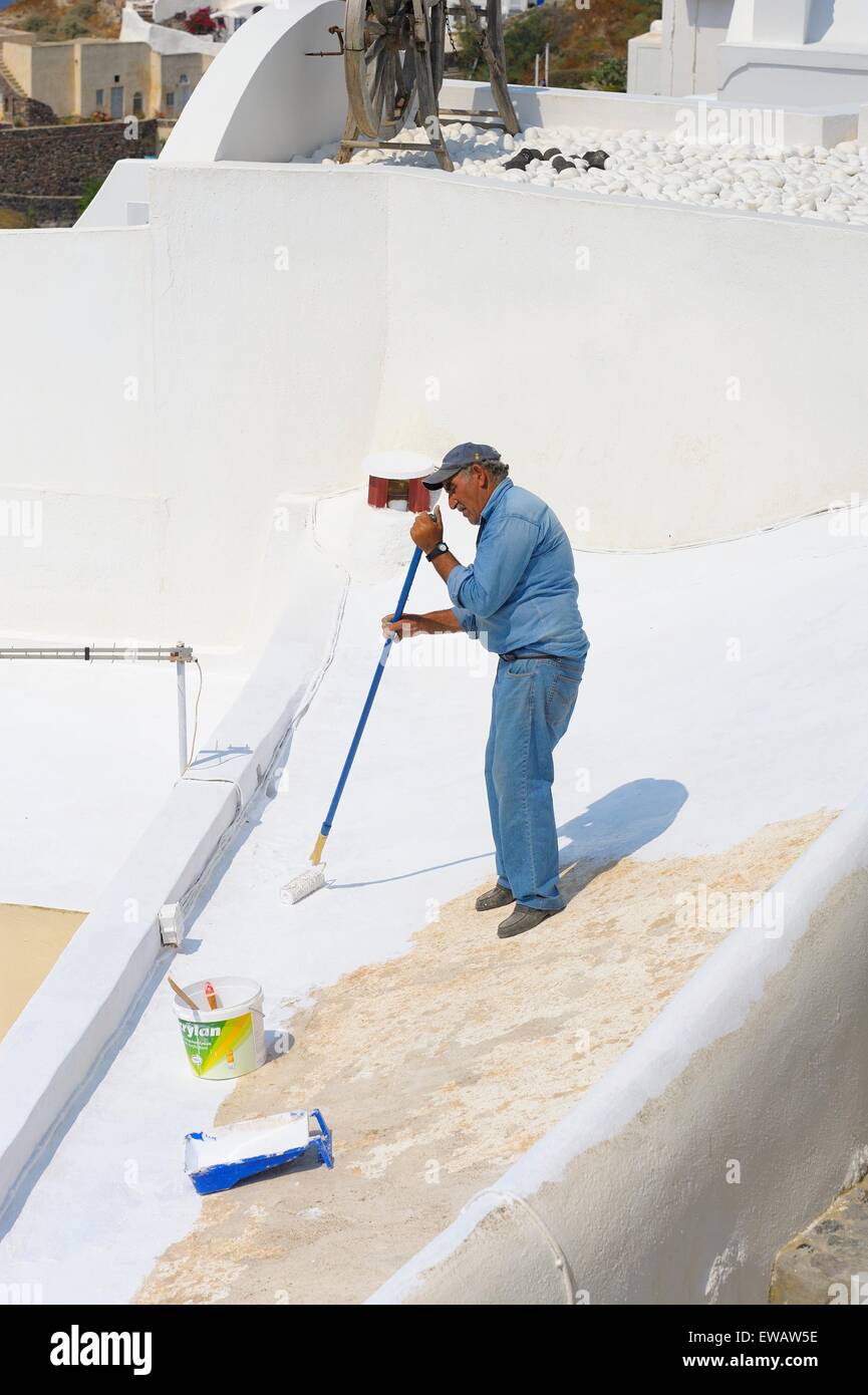 Un habitant de la peinture les toits de bâtiments situés dans le village de Oia, Santorin, Grèce Banque D'Images
