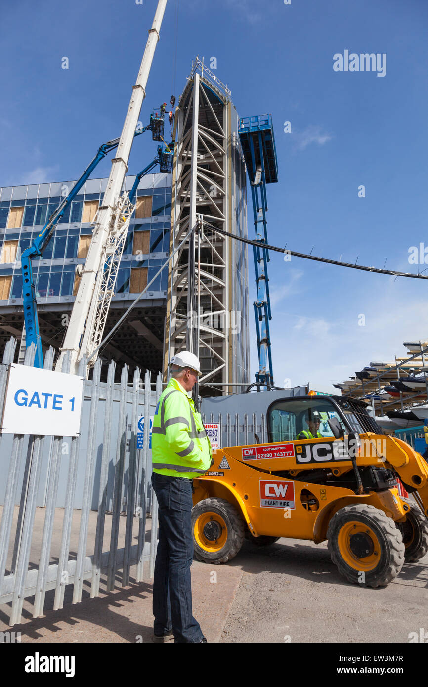 Un garde de sécurité se trouve à l'extérieur du site de construction de la quasi-Ben Ainslie Racing Team AC le Dock de carrossage, Portsmouth. Banque D'Images