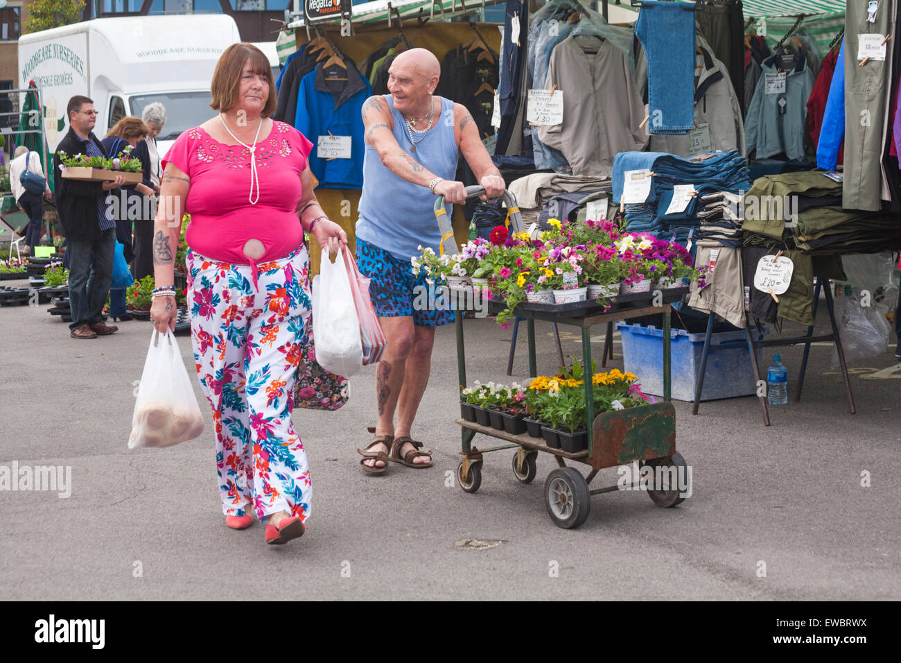 Couple walking through marché avec leurs achats au marché de Dorchester, Dorset, UK en Juin Banque D'Images