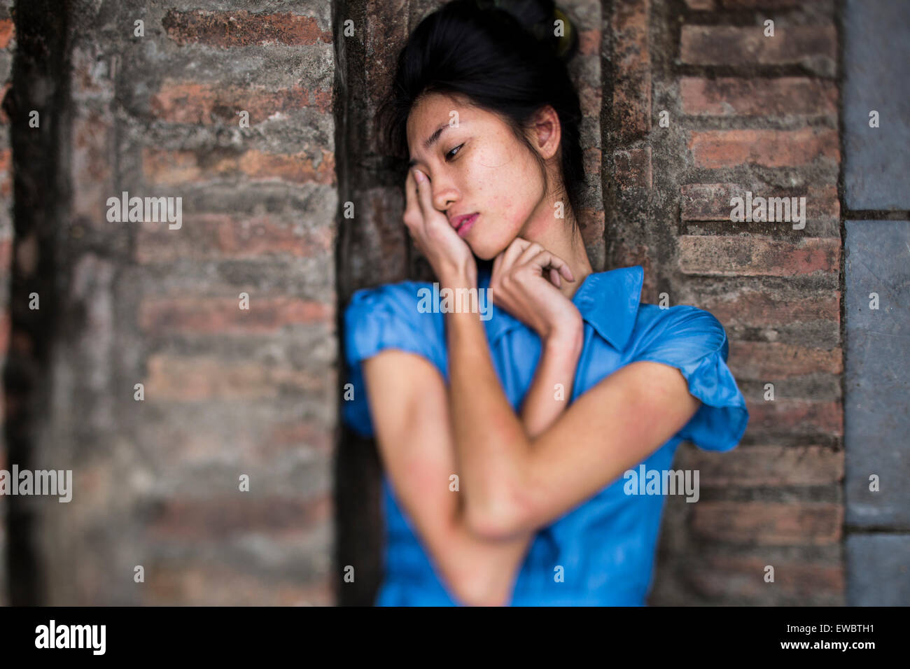 Une jeune vietnamienne dans une robe bleue, couché sur des marches en pierre dans les régions rurales de Hanoi, Vietnam. Banque D'Images