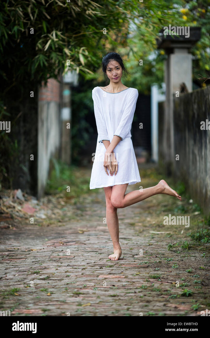 Une vietnamienne dans une robe blanche dans un milieu rural alley à Hanoï, au Vietnam. Banque D'Images