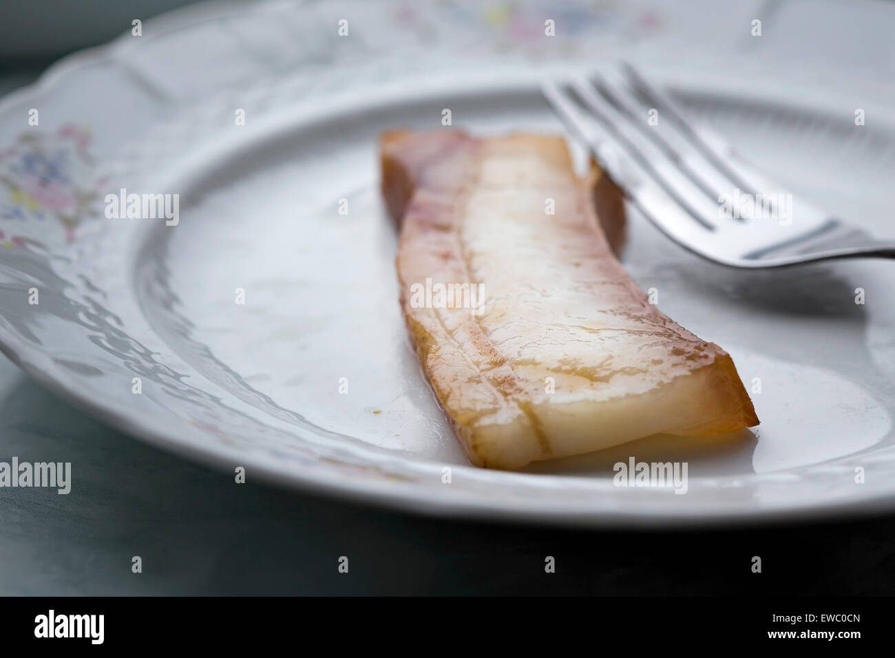 Un morceau de bacon grillé sur une assiette avec une fourchette Banque D'Images