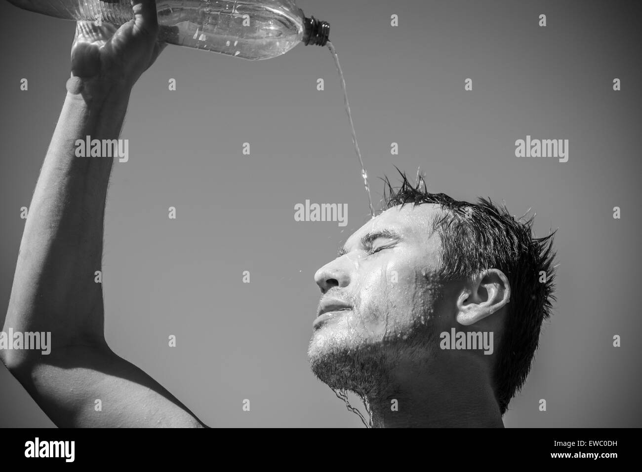 Photo d'un homme qui est couvert le visage avec de l'eau. Beau ciel en arrière-plan. Banque D'Images