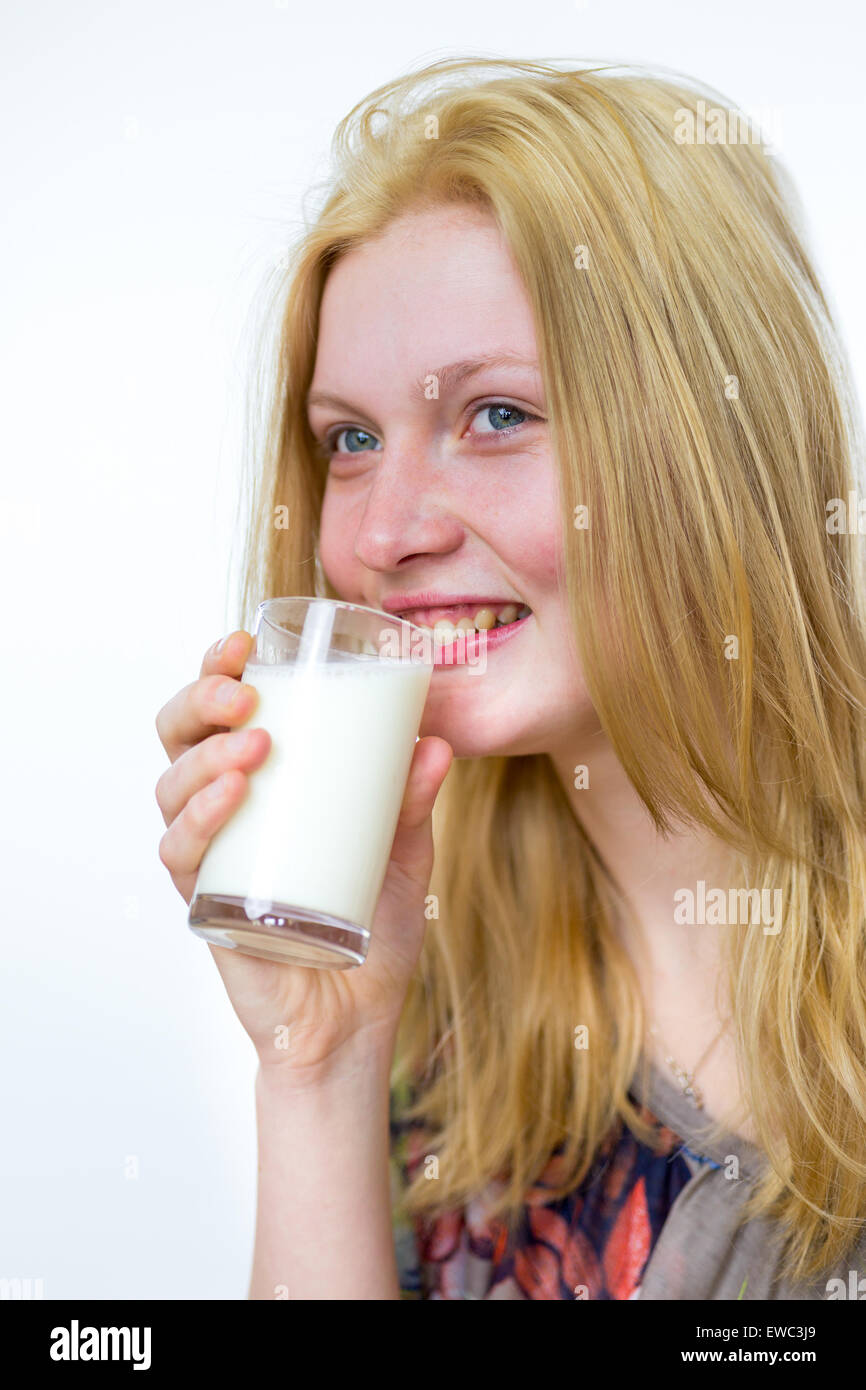 Blond caucasian teenage girl drinking verre de lait isolé sur fond blanc Banque D'Images