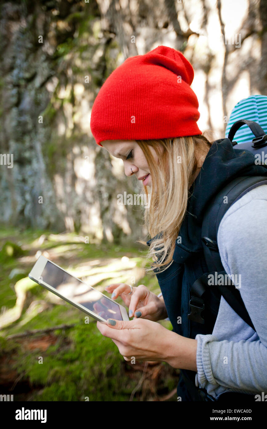 Une jeune femme travaille sur son comprimé tout en marchant à travers la forêt. Banque D'Images