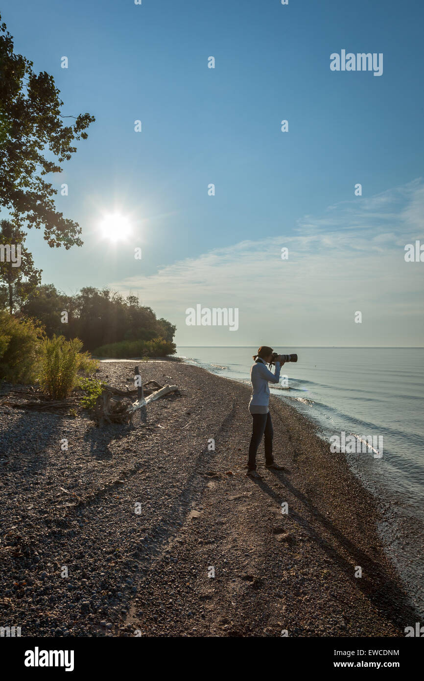 Une jeune femme avec un appareil photo, prise d'une photo sur une plage. Banque D'Images