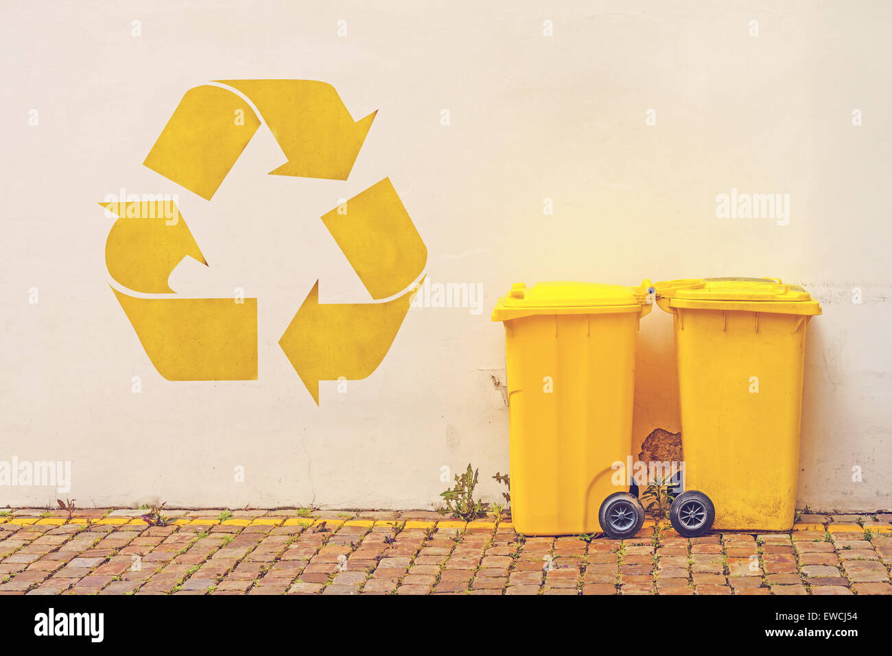 Deux bacs de recyclage en plastique jaune dans la rue contre le mur blanc avec réutilisent le graffiti au pochoir, tonique libre Banque D'Images