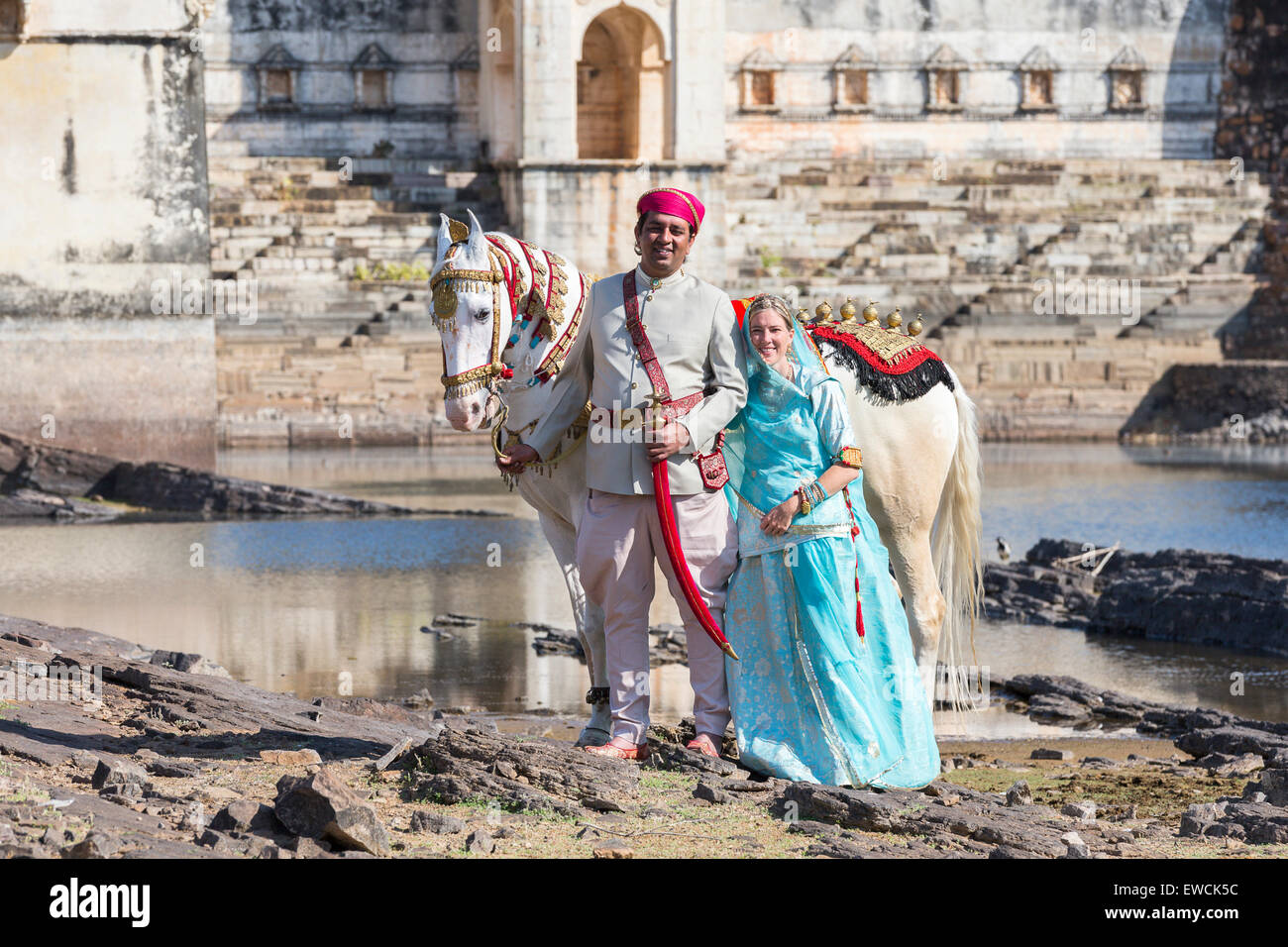 Chevaux Marwari. Cheval blanc dominant décoré en or, argent et bijoux debout à côté d'un couple en costume traditionnel. Chittor Banque D'Images