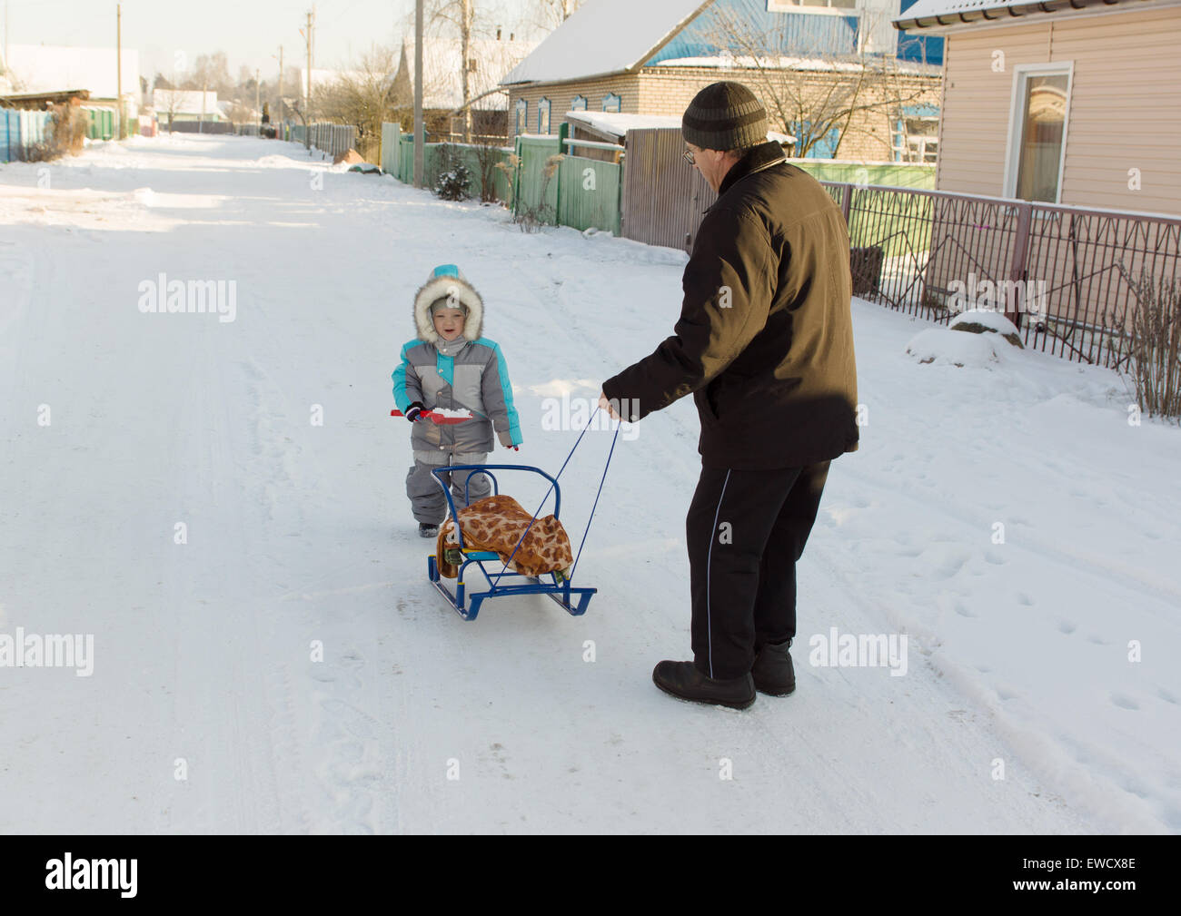 Chaudement vêtus de salopettes garçon avec grand-père jouant dans la rue l'hiver enneigé Banque D'Images