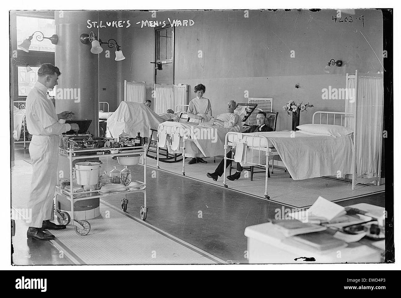 Cette image historique montre le service des hommes au sein de Luke, illustrant le rôle de l'hôpital dans les soins de santé à son époque. La photographie met en évidence la structure du service, les patients et le personnel médical fournissant des soins dans un cadre de soins vintage. Banque D'Images