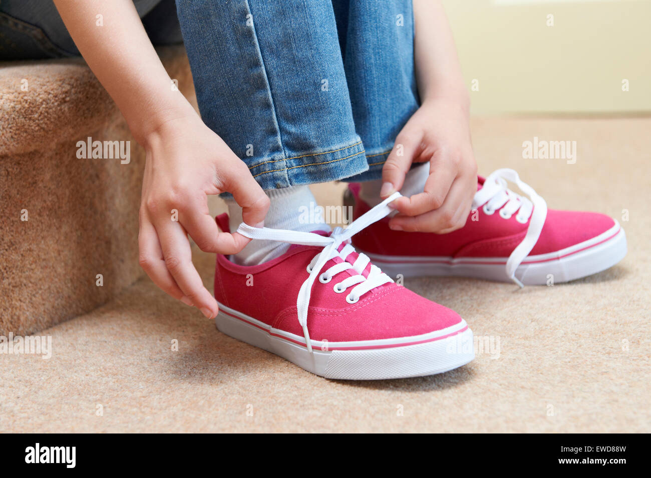 Girl Sitting on Stairs et attacher ses lacets Banque D'Images