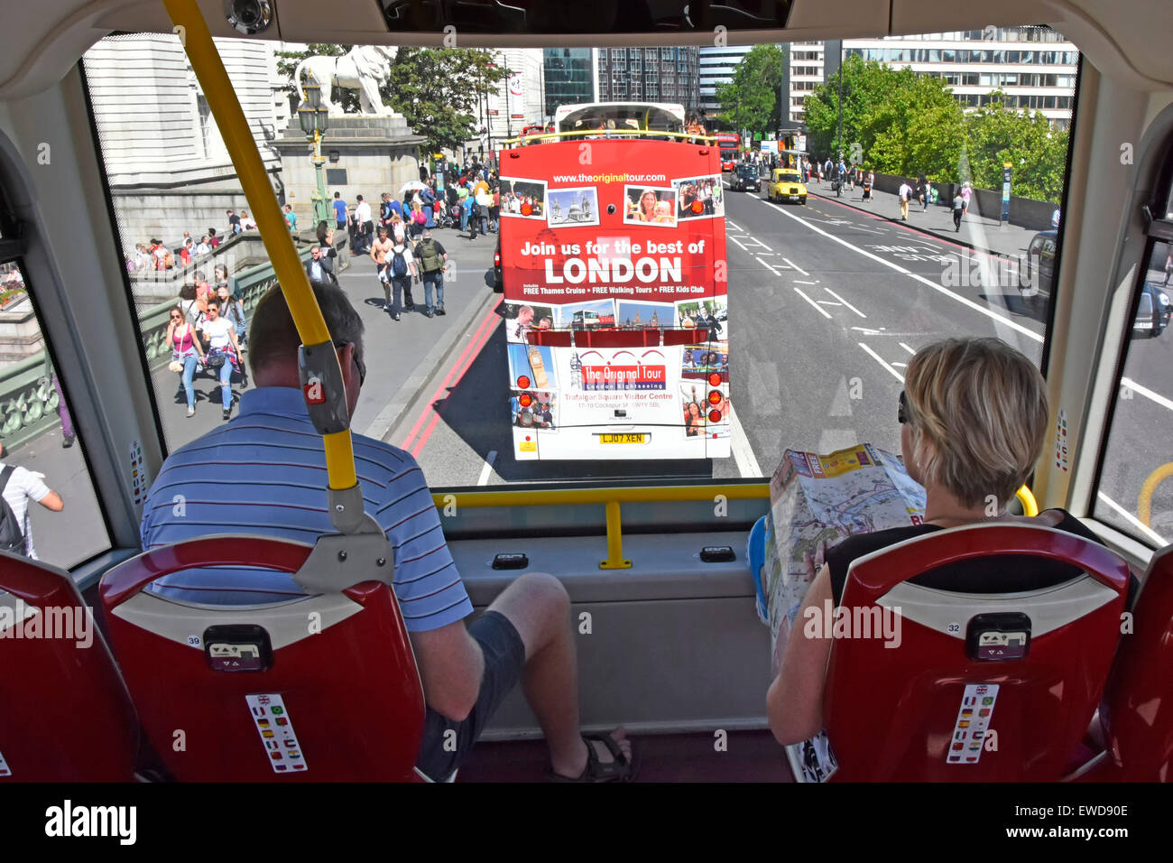 Titulaire d'une carte touristique assis sur les sièges avant du plateau supérieur du tour bus traversant la Tamise à Westminster Bridge plus d'autobus devant London England UK Banque D'Images