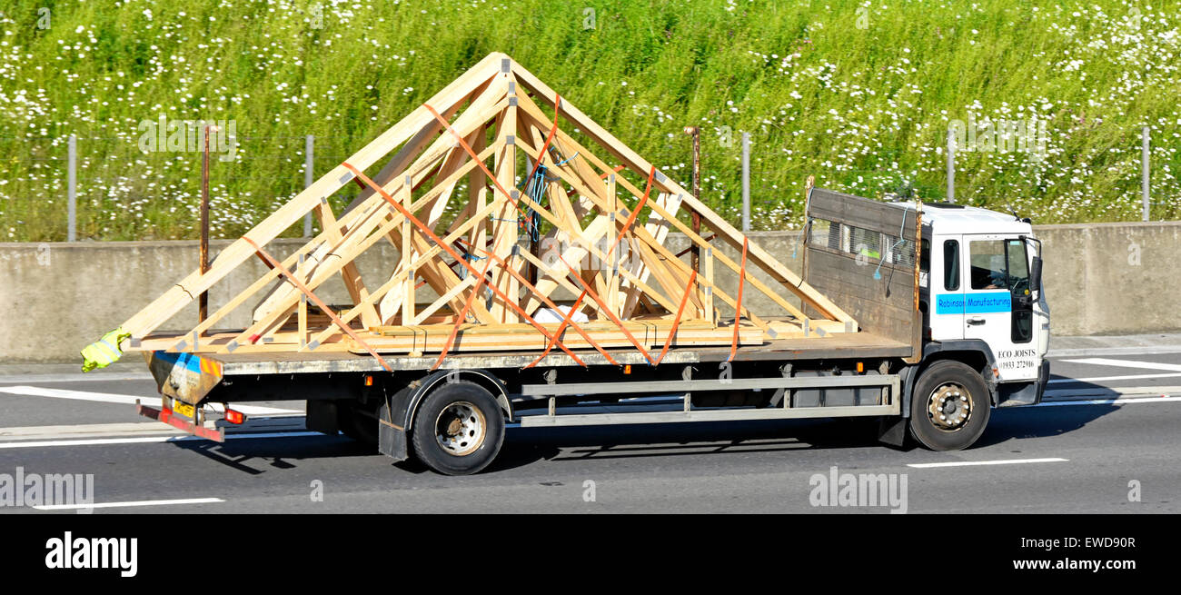 Chargement de camion camion bois assemblés en usine fermes de toit préfabriquées matériaux de construction sur camion à plateau lit plat de la conduite sur autoroute England UK Banque D'Images