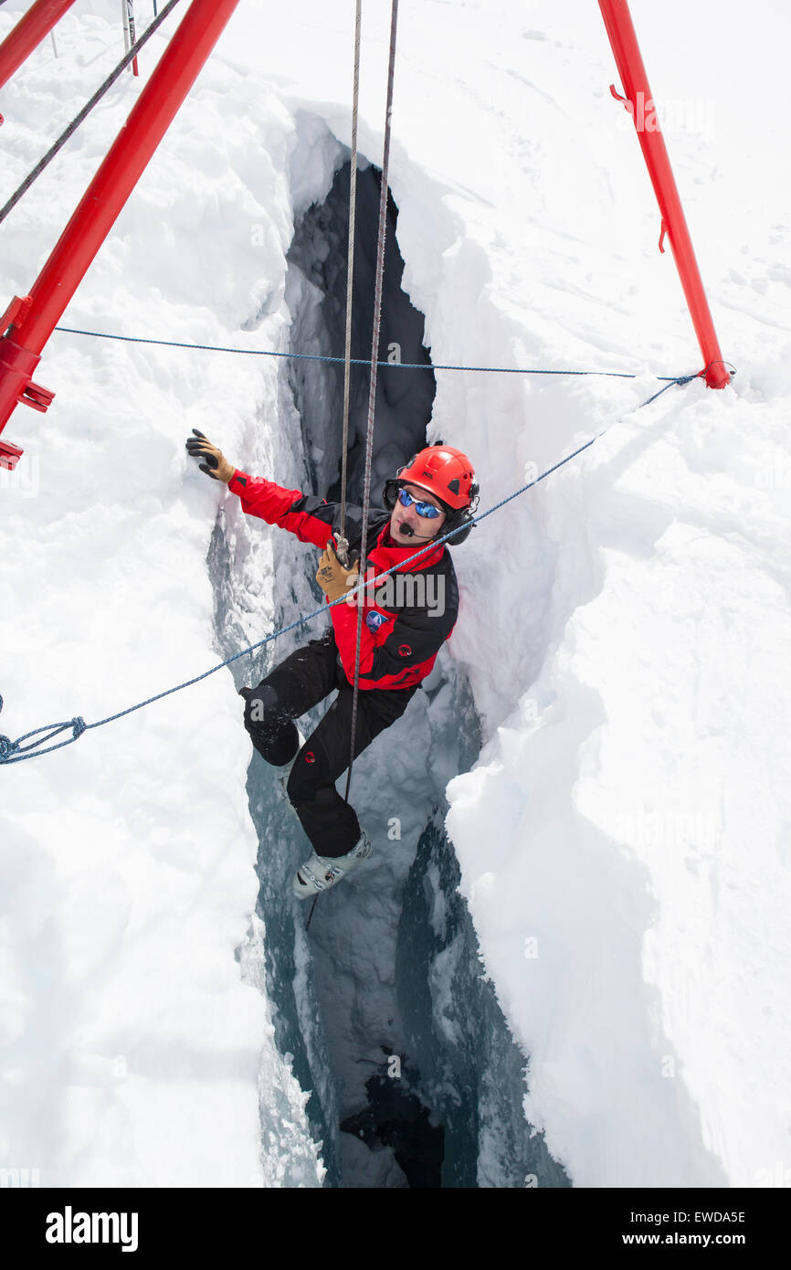 Un technicien de sauvetage en montagne est en ordre décroissant dans une crevasse. Lorsqu'un skieur se brise à travers la neige et dégringole le glacier Banque D'Images