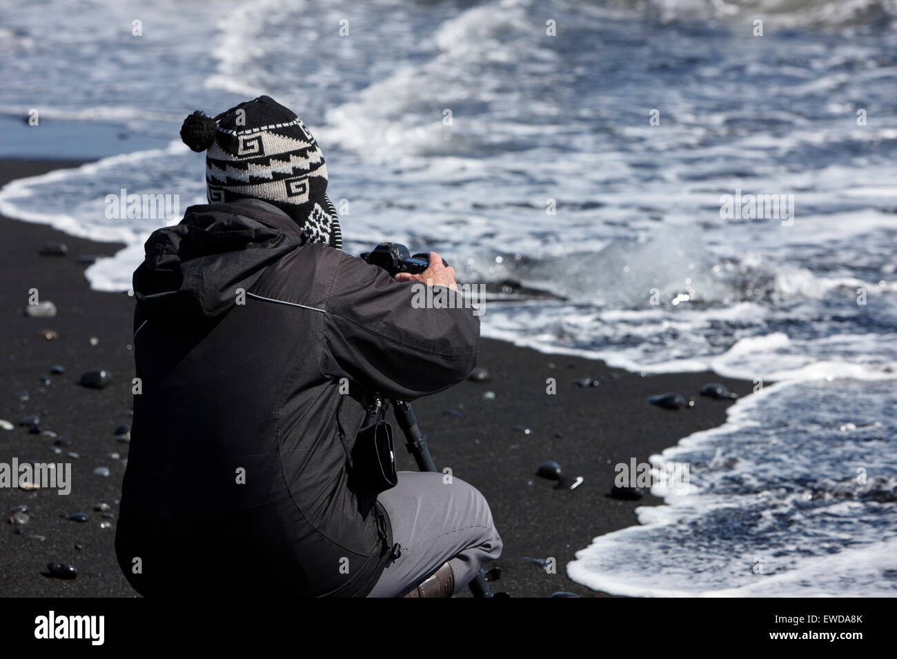 Photographe à prendre des photos d'icebergs rejetés sur la plage de sable noir à l'Islande Jokulsarlon Banque D'Images