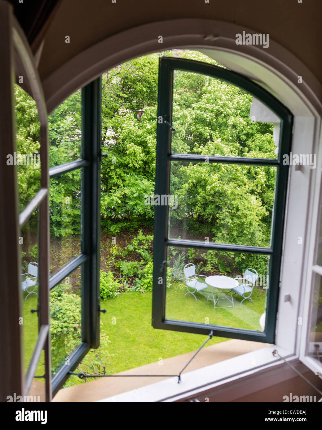 Voir à travers les fenêtres ouvertes pour le vert jardin pelouse avec meubles de style café Banque D'Images