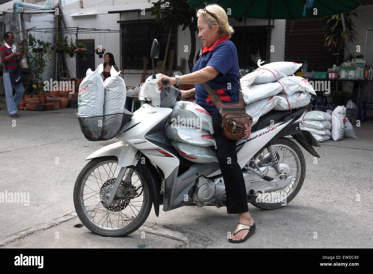 La femme sa moto surchargée après un voyage dans le marché local à Pattaya en Thaïlande Banque D'Images