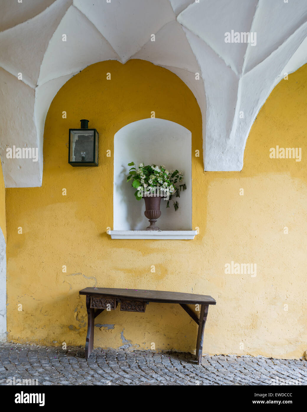 Banc en bois contre le mur en pierre jaune dans l'entrée avec plafond voûté arch Banque D'Images