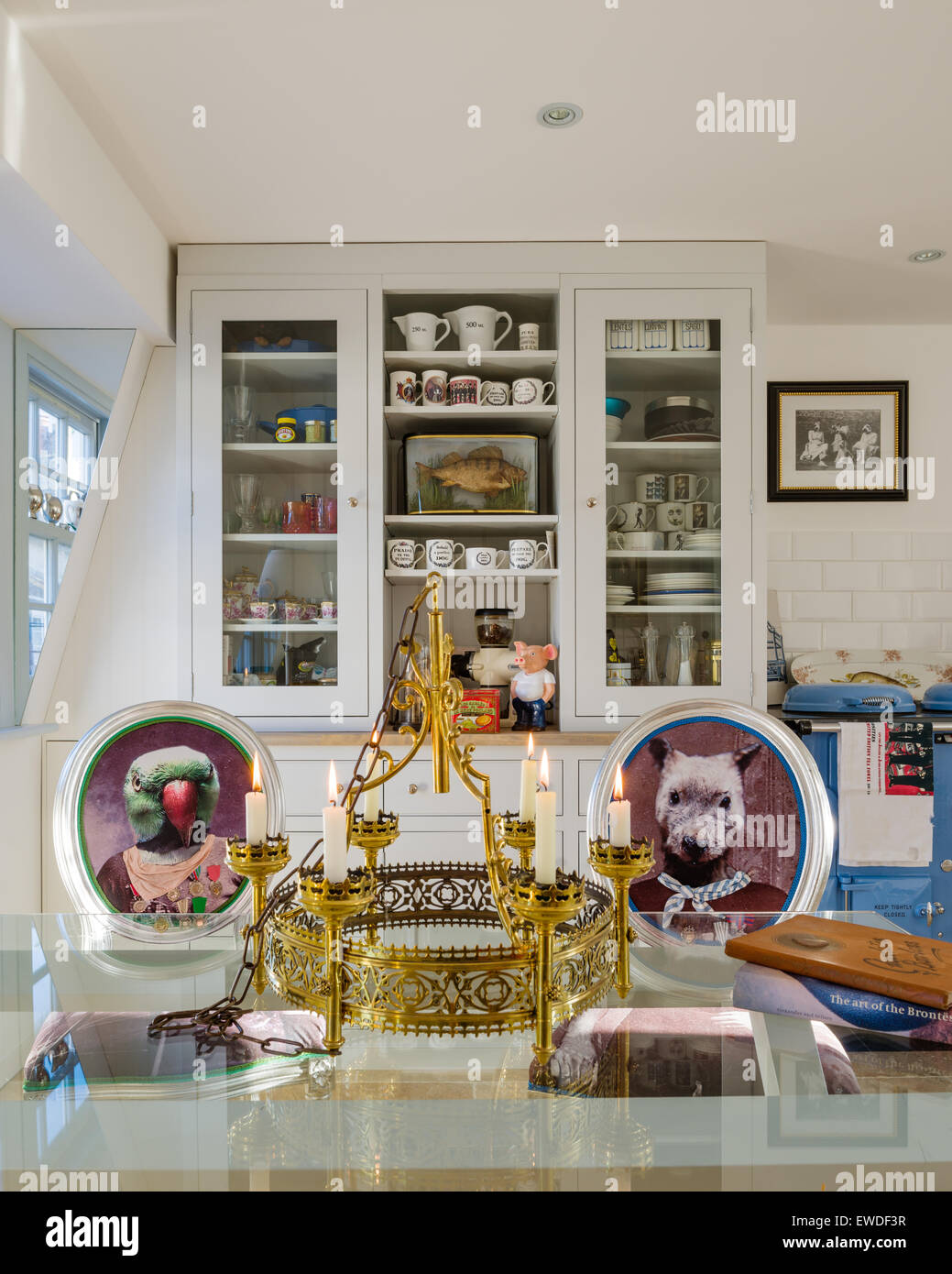Chaise de salle à manger Meubles dans Visitorian Cory imprime autour d'une table à manger en verre surmontée cuisine avec vaisselier blanc et aga Banque D'Images