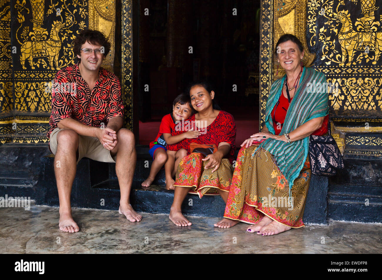 Famille dans l'embrasure de Wat Xieng Thong (Temple de la ville d'Or) , construit en 1560 - LUANG PRABANG, LAOS M. Banque D'Images
