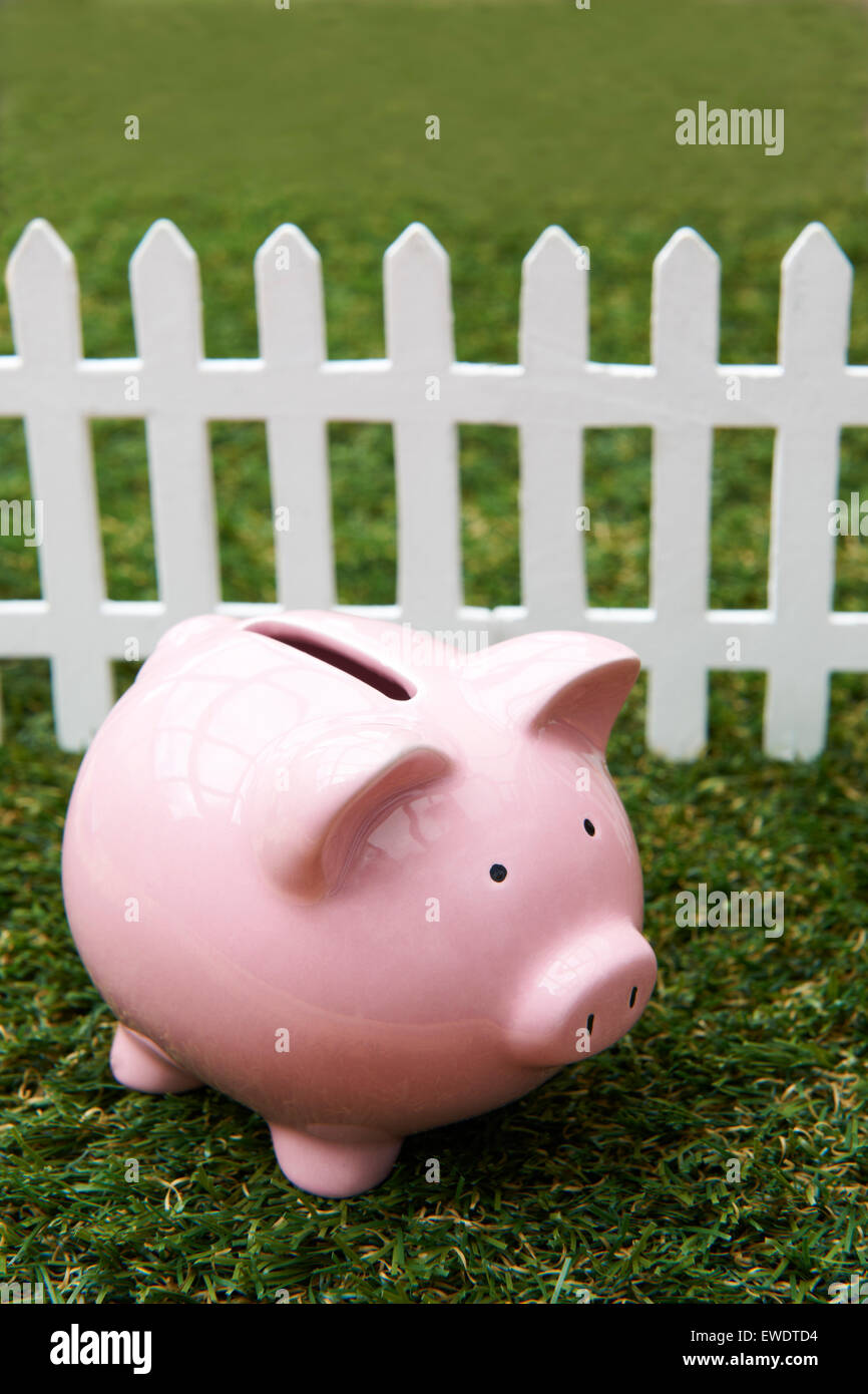 Tirelire sur herbe avec clôture blanche Banque D'Images