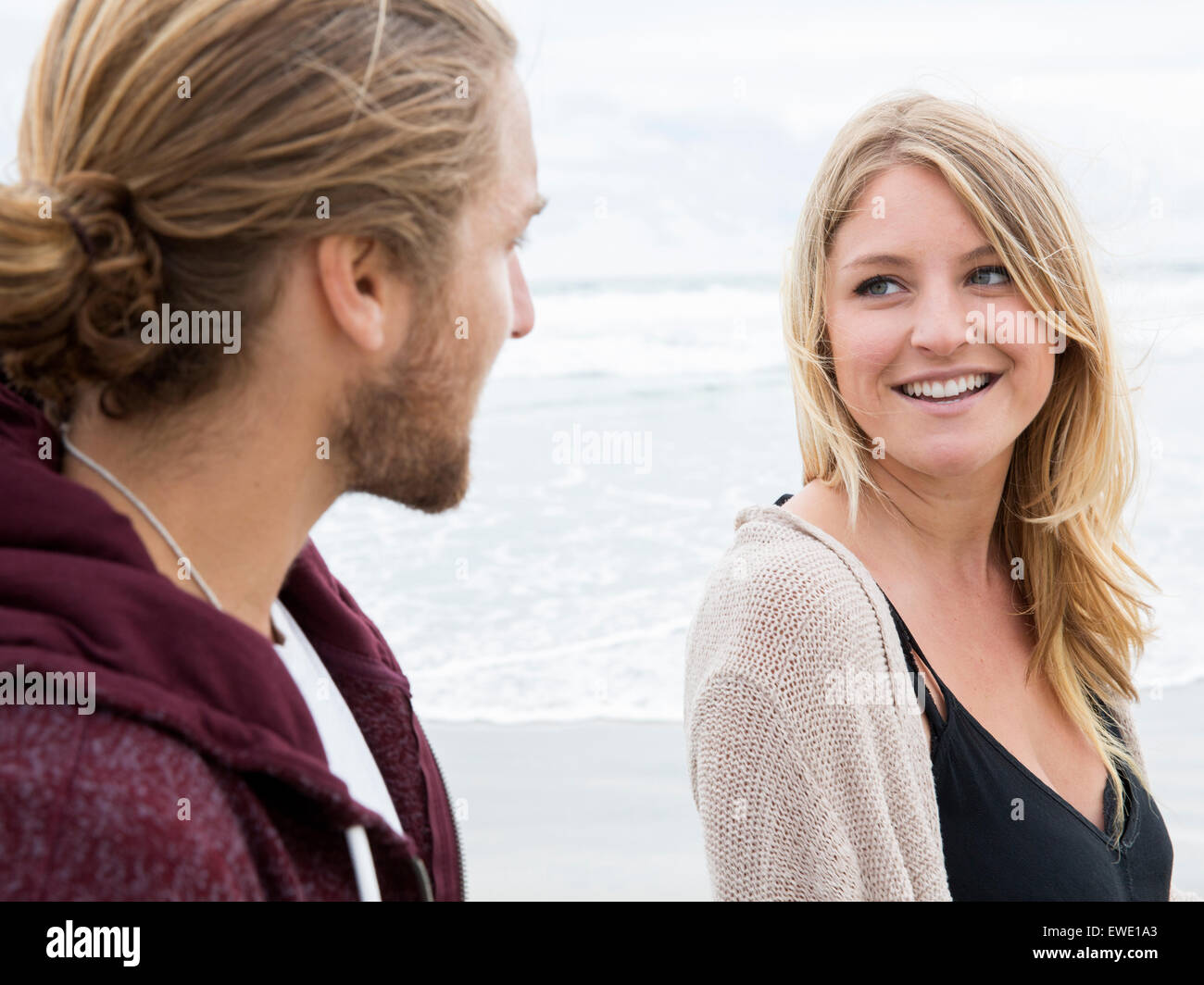 Jeune homme et la jeune femme sur une plage, se regarder, smiling Banque D'Images