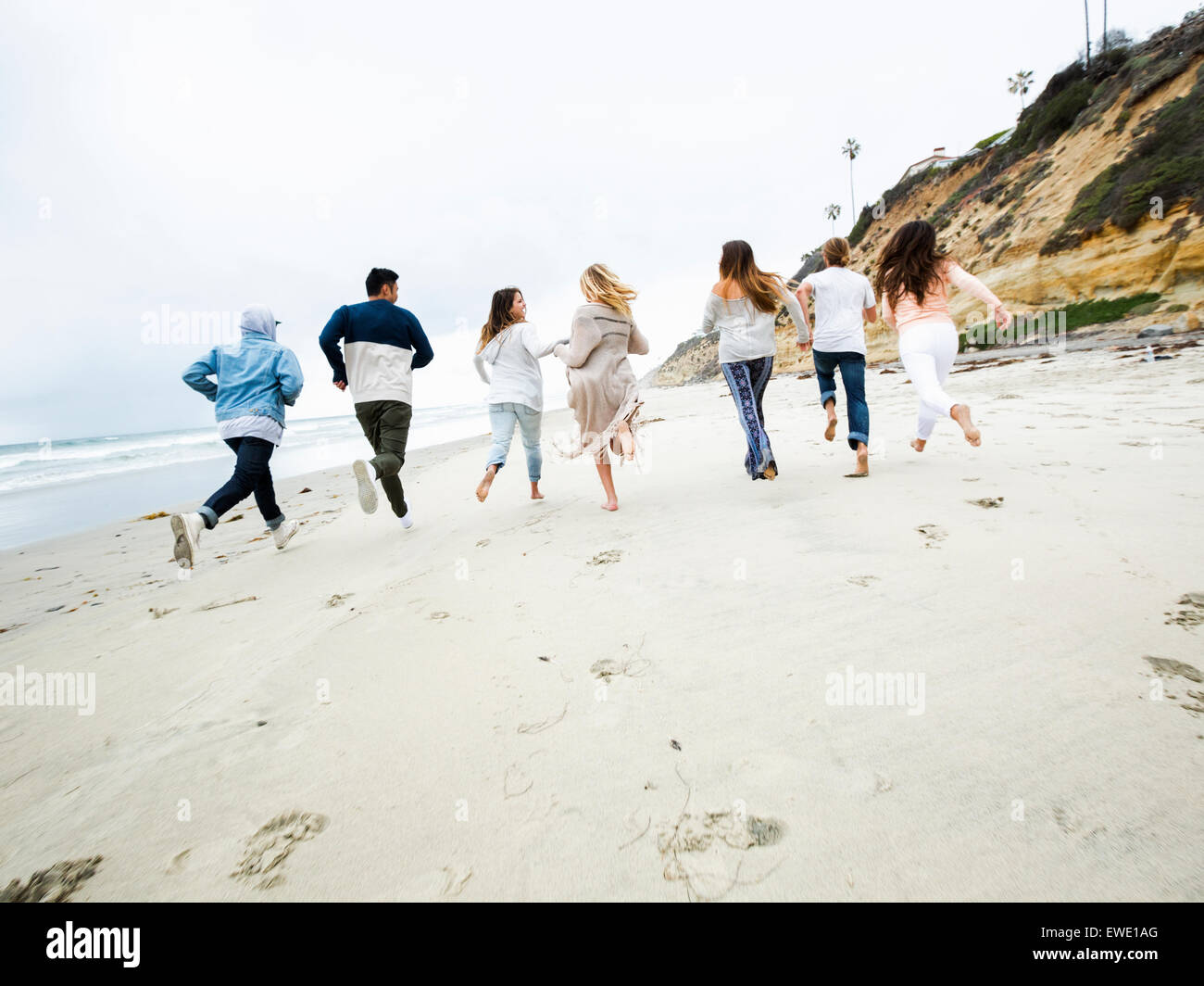 Un groupe de jeunes hommes et femmes s'exécutant sur une plage, s'amusant Banque D'Images
