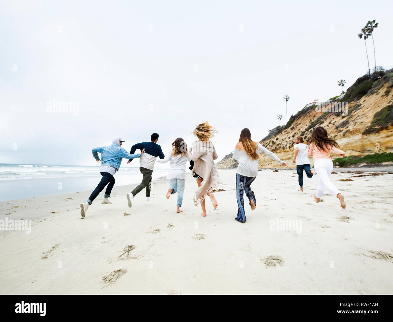 Un groupe de jeunes hommes et femmes s'exécutant sur une plage, s'amusant Banque D'Images