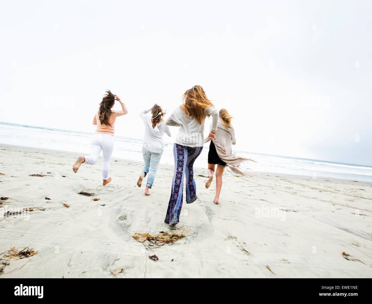 Un groupe de jeunes hommes et femmes s'exécutant sur une plage, s'amusant Banque D'Images