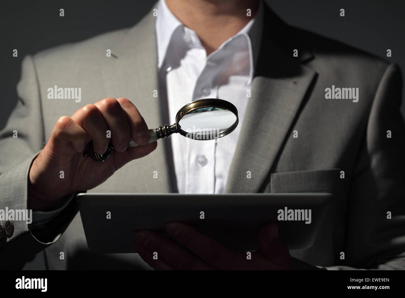 Businessman holding magnifying glass and digital tablet concept pour la recherche sur internet, recherche d'un emploi ou l'analyse des comptes publics Banque D'Images