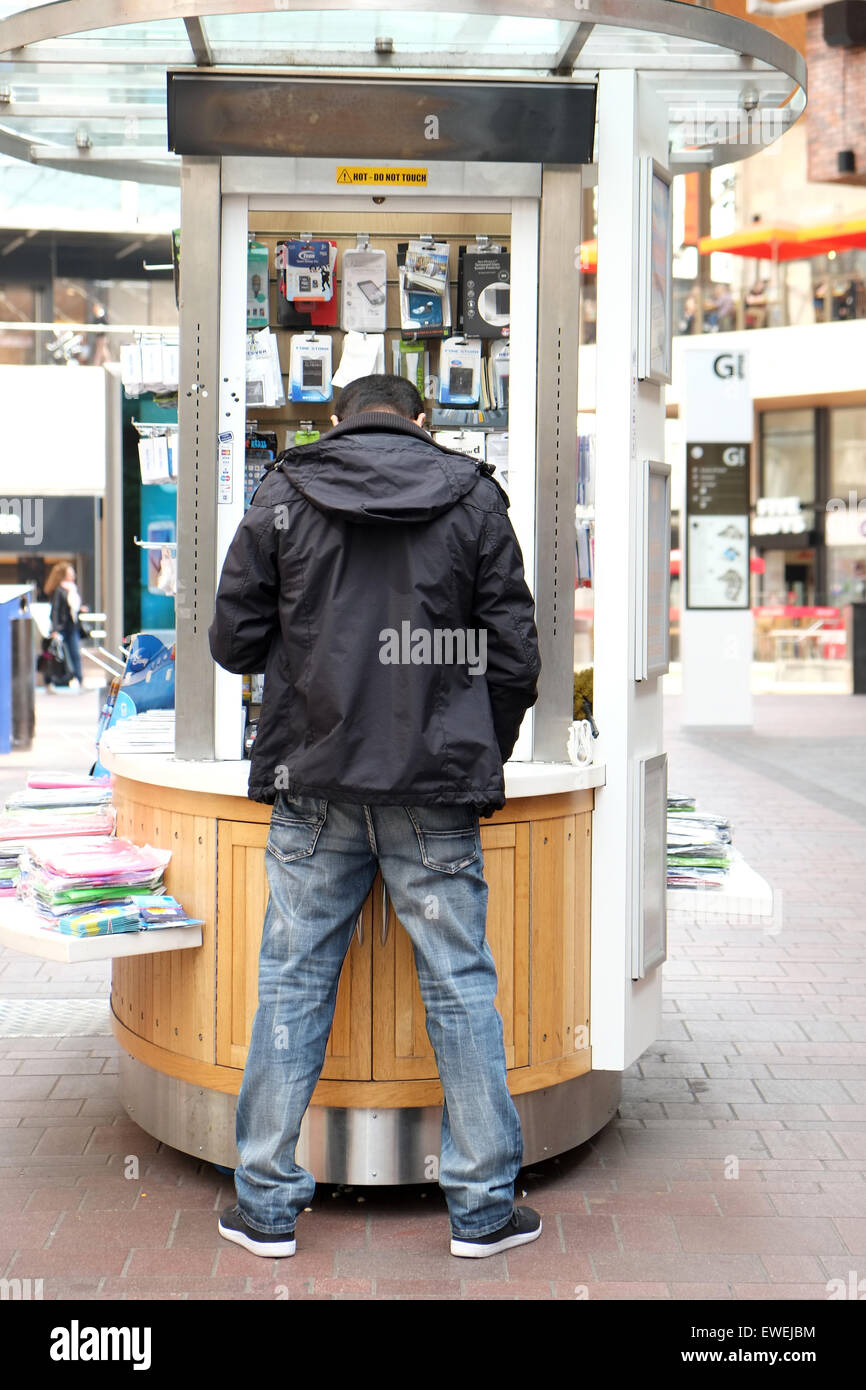 Vue arrière d'un homme vendant des accessoires de téléphone portable mobile à partir d'un panier dans un grand centre commercial à Bristol Banque D'Images