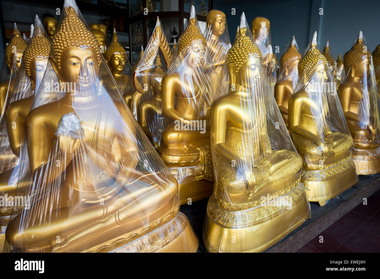Rangées de bouddhas assis d'or enveloppé dans du plastique dans un magasin spécialisé dans les fournitures pour les temples bouddhistes de Bangkok, Thaïlande Banque D'Images