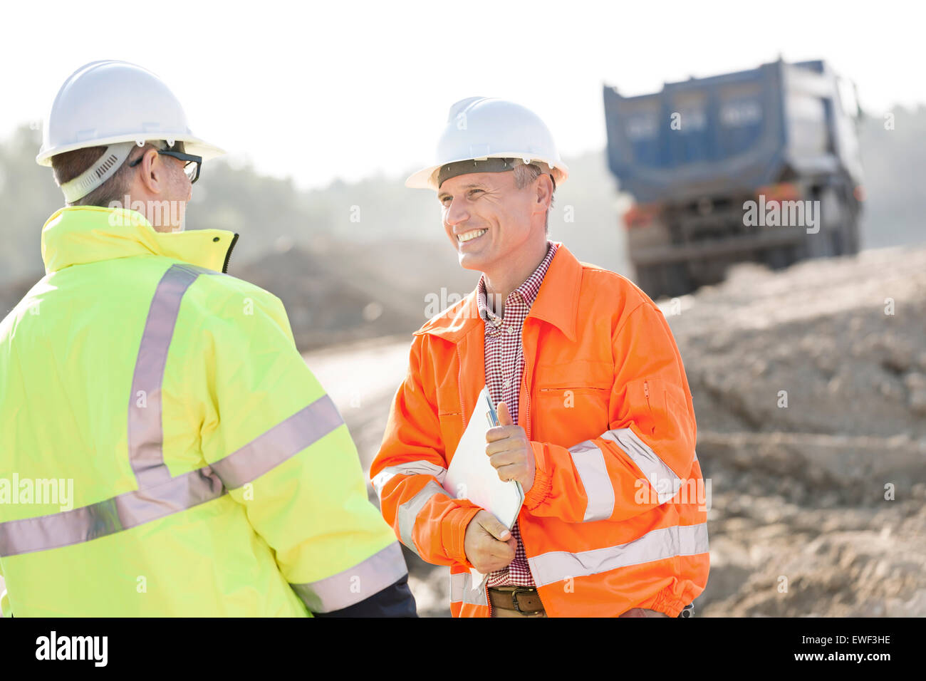 Ingénieur heureux de discuter avec collègue at construction site sur sunny day Banque D'Images