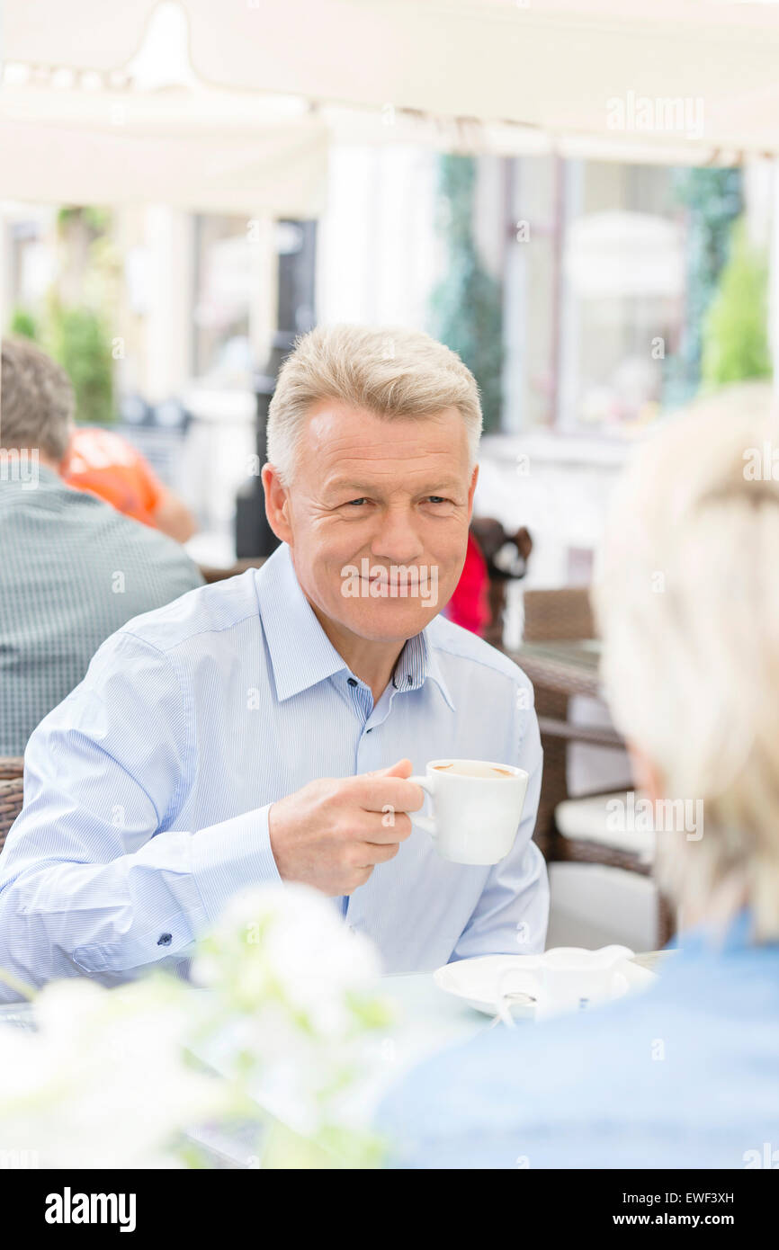 Smiling middle-aged man with woman having coffee at sidewalk cafe Banque D'Images