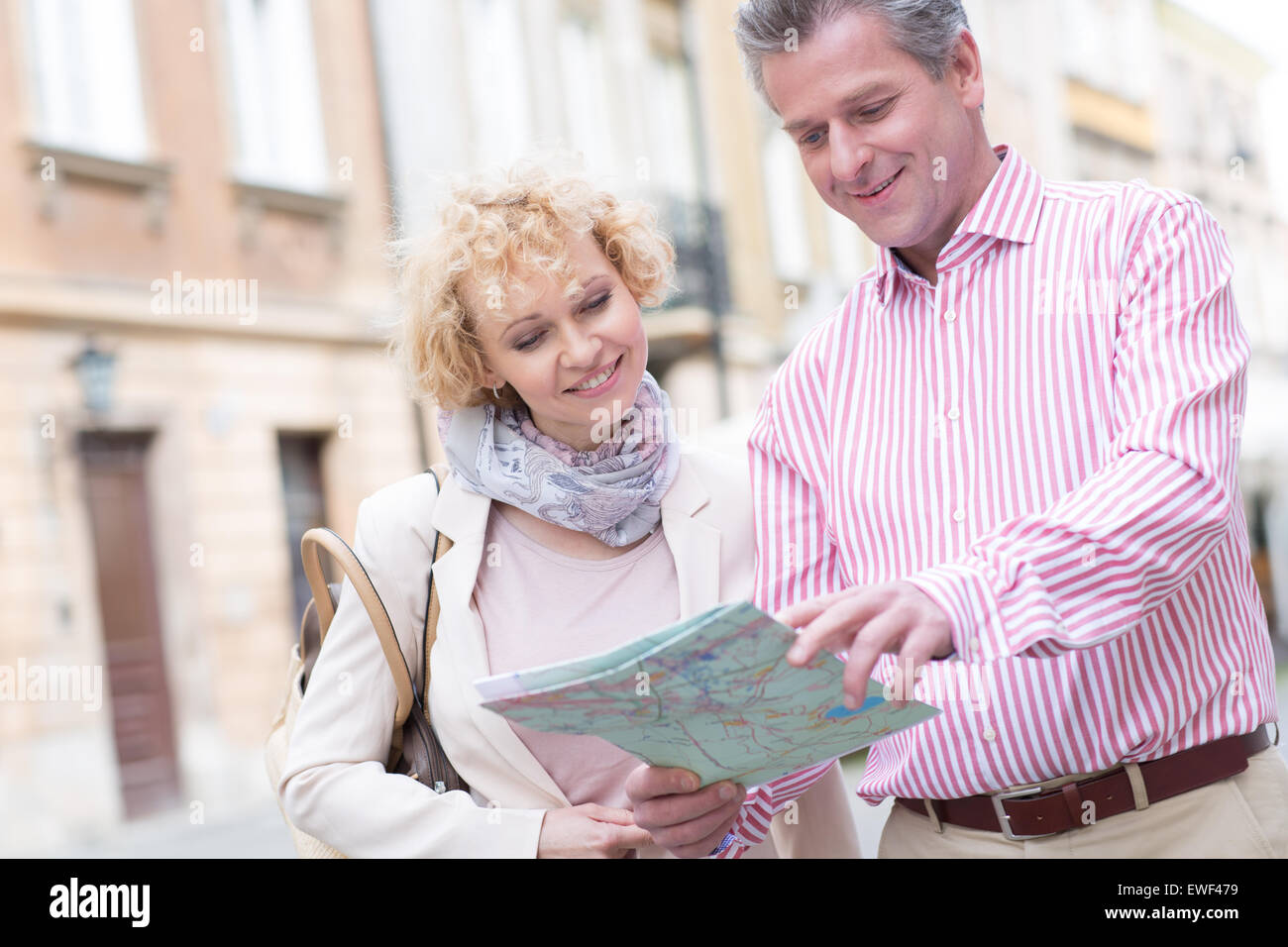 Smiling couple reading map in city Banque D'Images