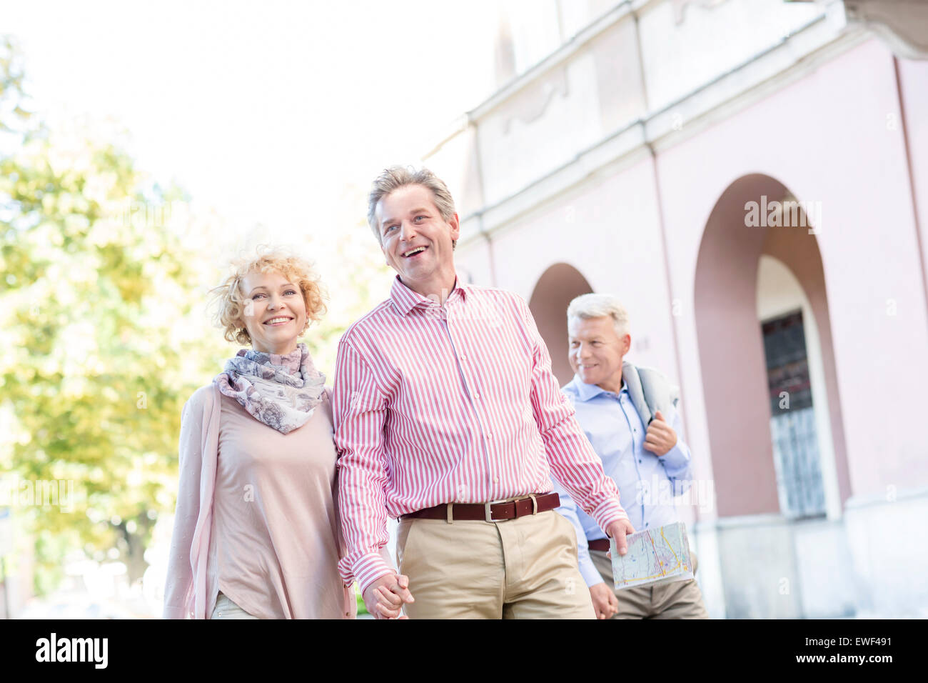 Happy middle-aged couple with map walking in city Banque D'Images