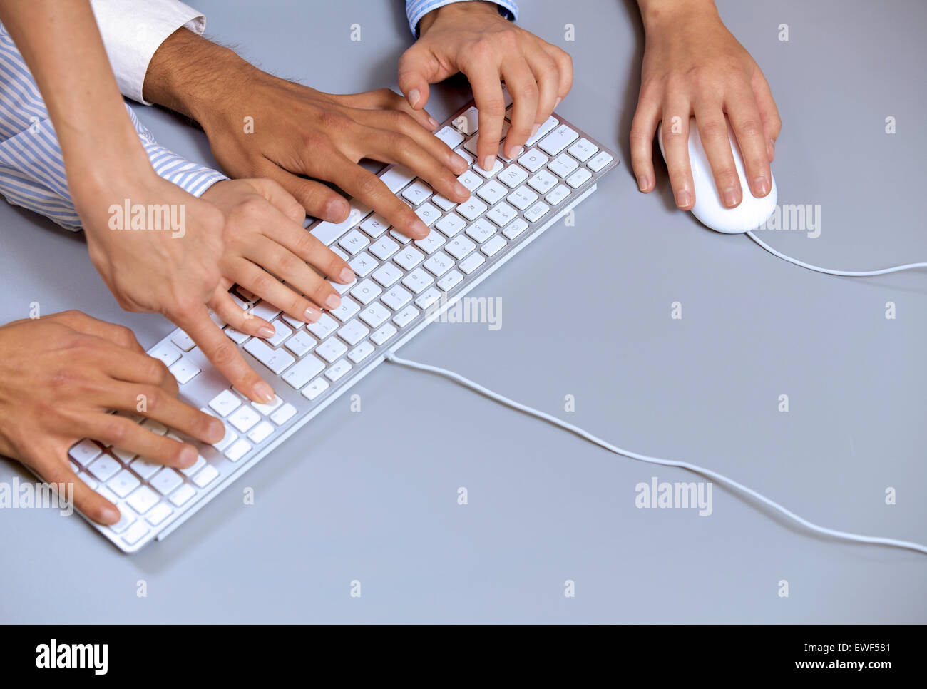 Des mains sur un clavier d'ordinateur avec une main à l'aide de la souris d'ordinateur Banque D'Images