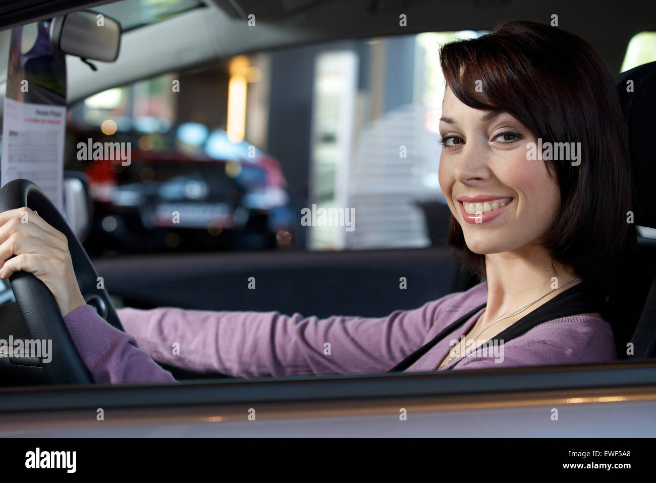 Portrait de jeune femme assise dans le siège du conducteur de voiture à dealersh Banque D'Images