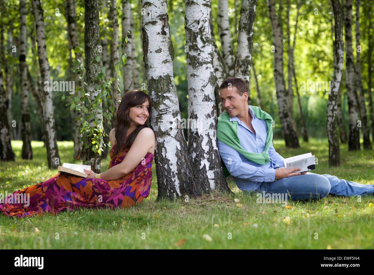 Young couple holding books dans le parc par tronc de l'arbre, à l'un l'autre Banque D'Images