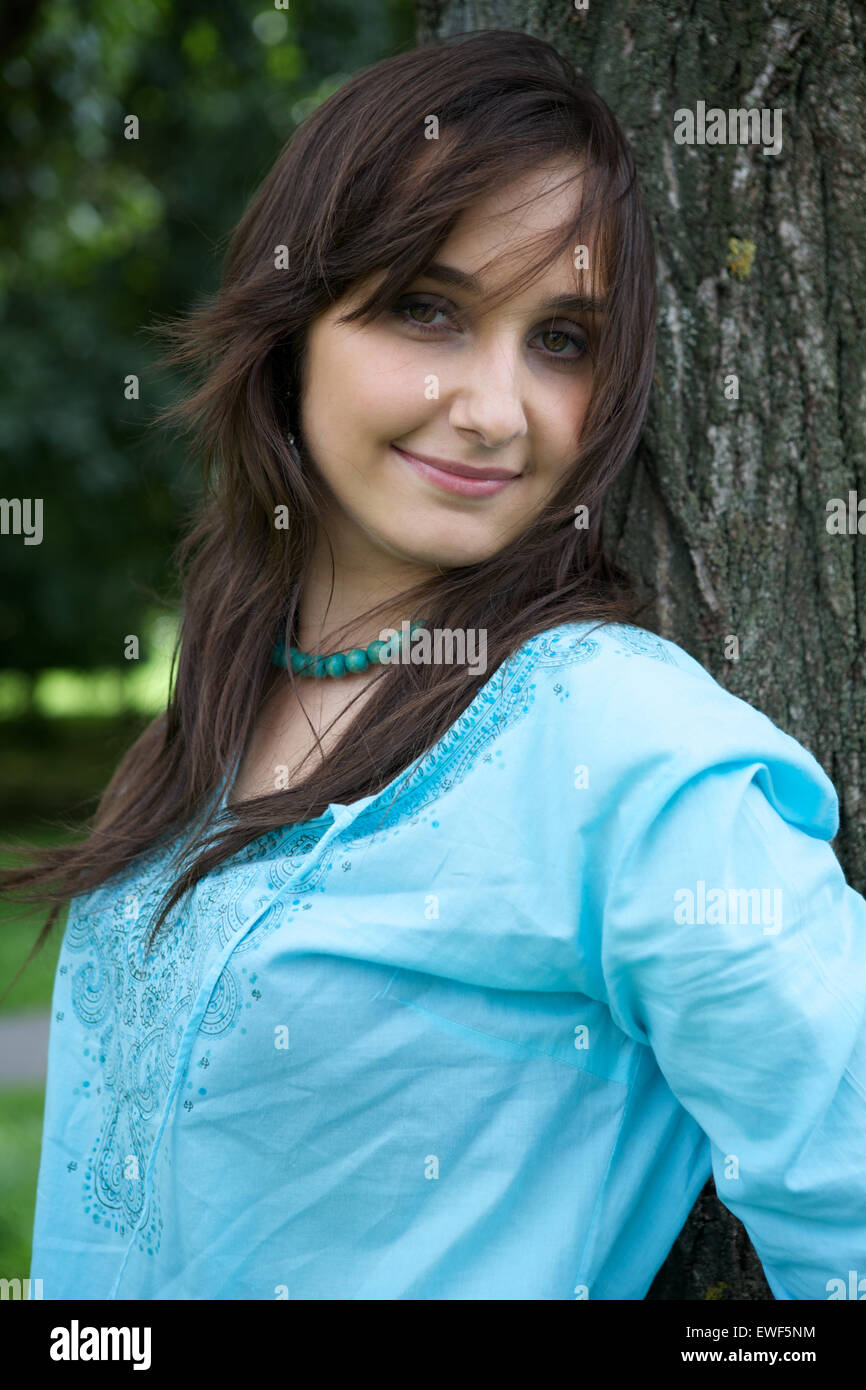 Portrait of young woman standing by tree and smiling Banque D'Images