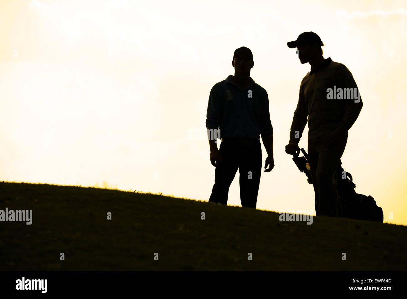 Silhouette de jeunes hommes en permanent avec chariot de golf Banque D'Images