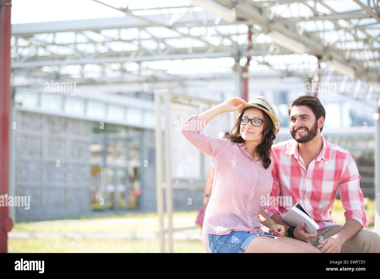 Couple heureux à l'écart tout en étant assis sur un banc à l'ombre Banque D'Images