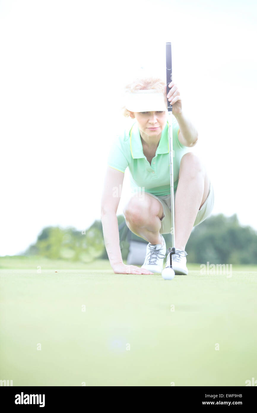 Femme d'âge moyen visant à golf course Banque D'Images