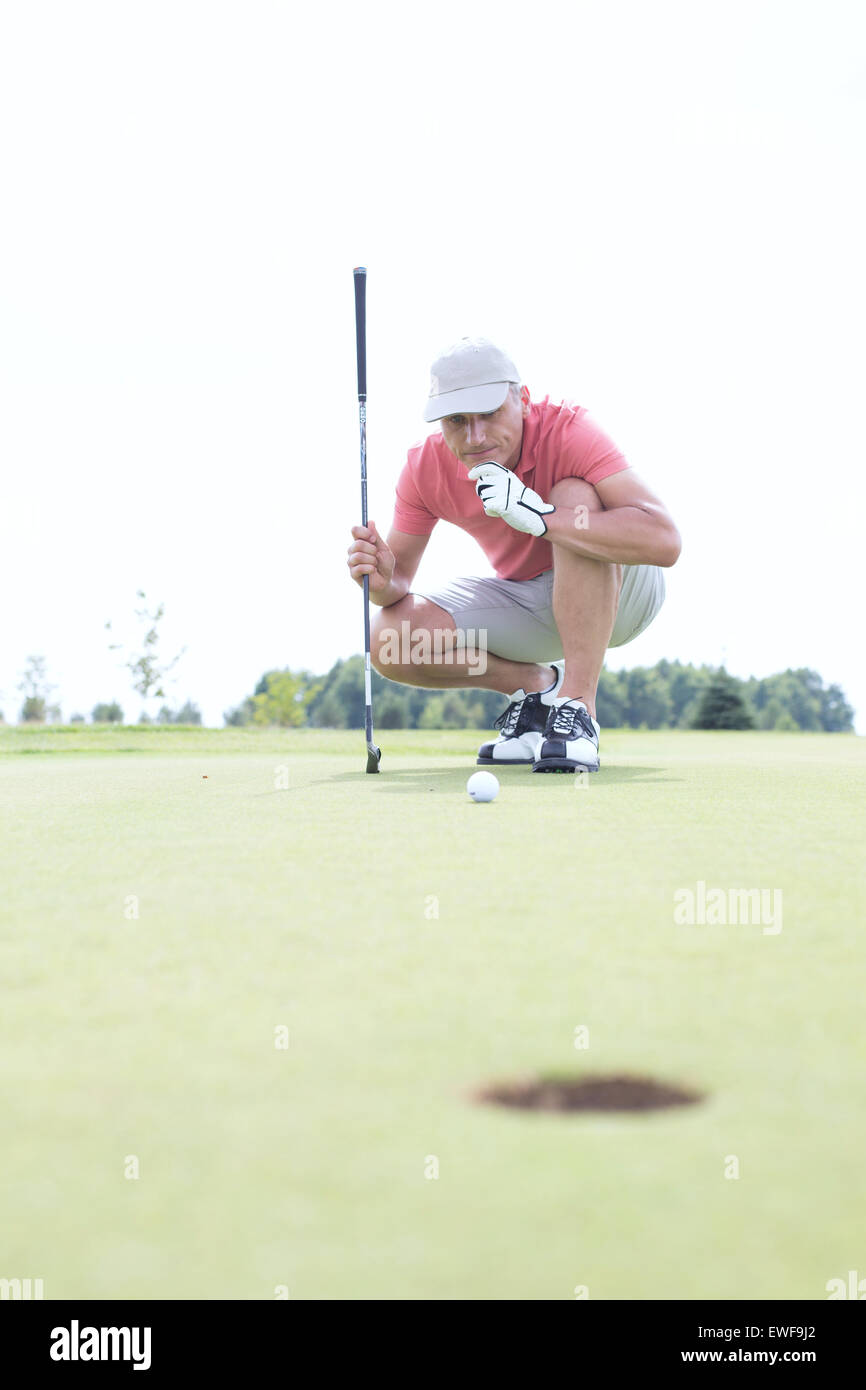 Homme d'âge moyen à la boule tout à crouching on golf course Banque D'Images