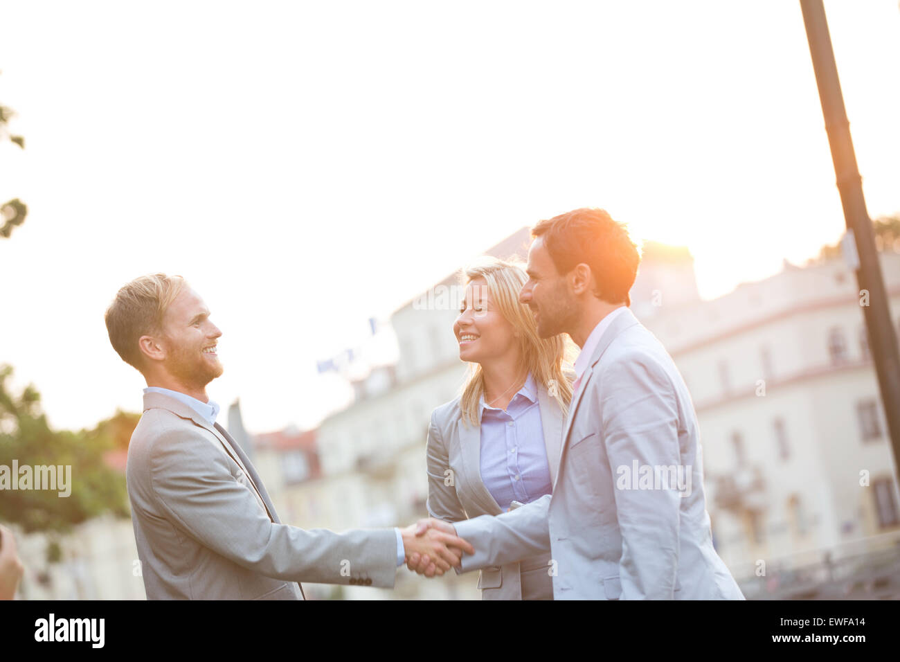 Happy businessmen shaking hands in ville contre un ciel clair Banque D'Images